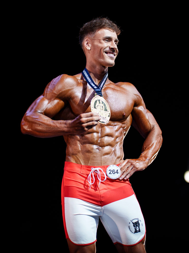 Entrenador posando con una medalla en una competición.